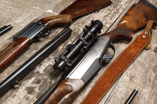 Many hunting rifles on weathered wooden surface