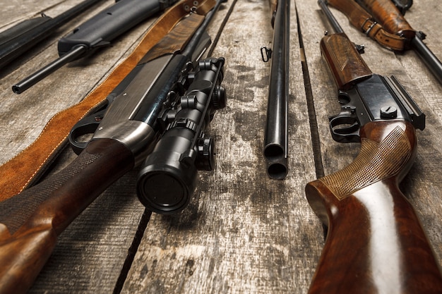 Many hunting rifles on weathered wooden surface