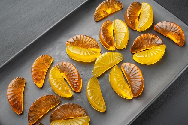 Many jelly citrus candy on a black dish on a dark background