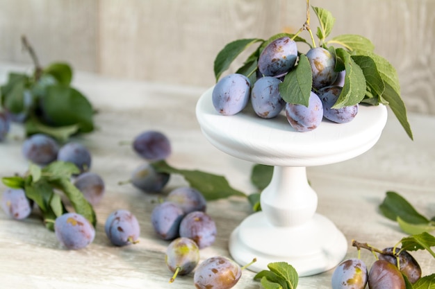 Many juicy beautiful amazing nice plums on light wooden background Beautiful food art background