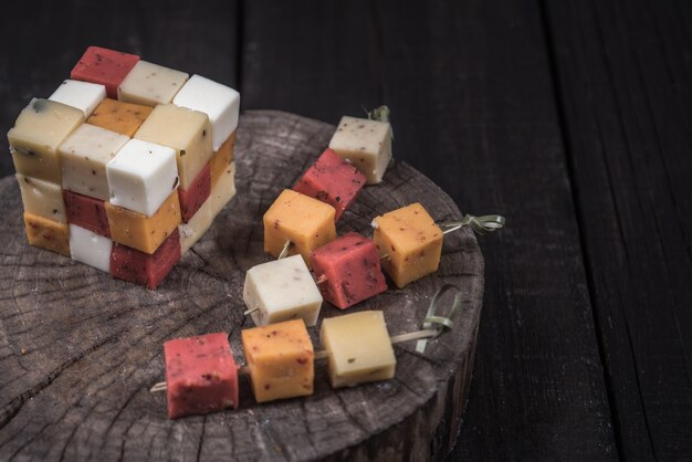 Many kinds of cheeses on wooden end of a tree