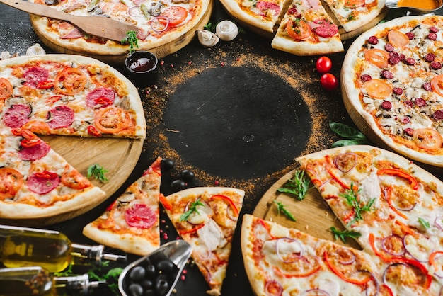 Много видов вкусной пиццы на черном фоне. Флэтлей. Копировать пространство