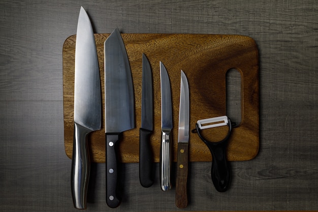 Many kitchen knives are placed on a cutting board.