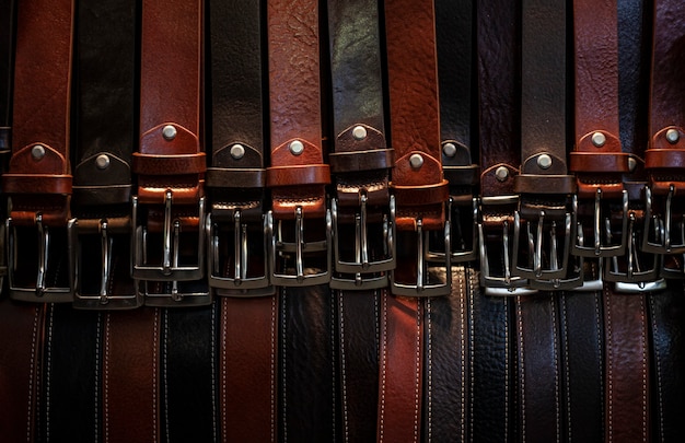 Many leather belts exposed all close together in a market for sale