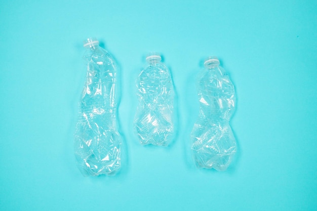 Many many used empty PET bottles on a blue background, top view. Recycling problem