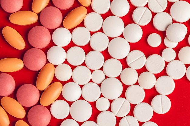 Many medicine pills close up on red 