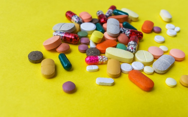 many medicine on yellow background closeup of multicolored medicine tablets capsules and pills