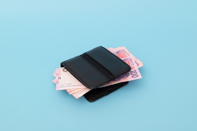 Many money in a wallet on a blue background. Ukrainian hryvnias