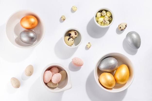 Many multi-colored Easter eggs in bowls of different sizes on a white table