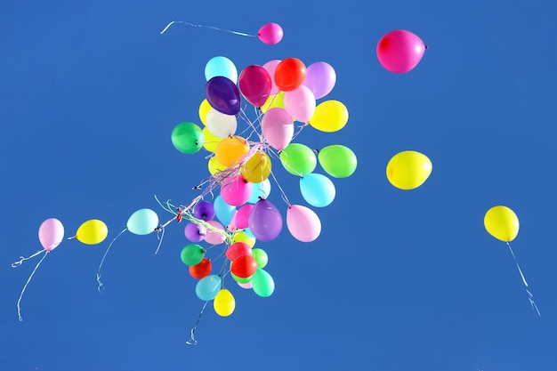 Many multicolored balloons flying in the blue sky holiday accessories and decorations