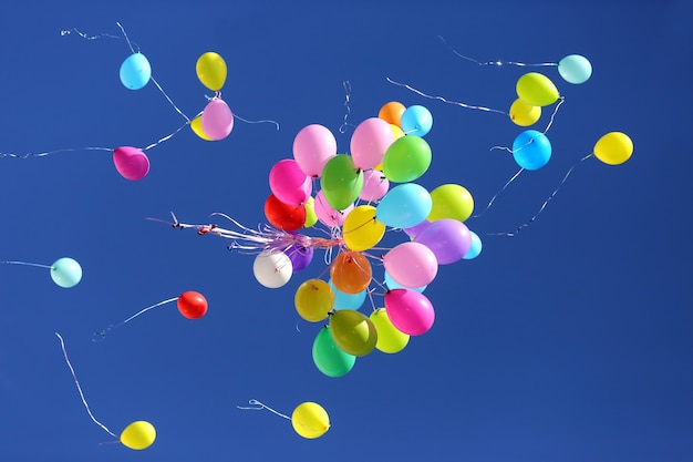 Many multicolored balloons flying in the blue sky