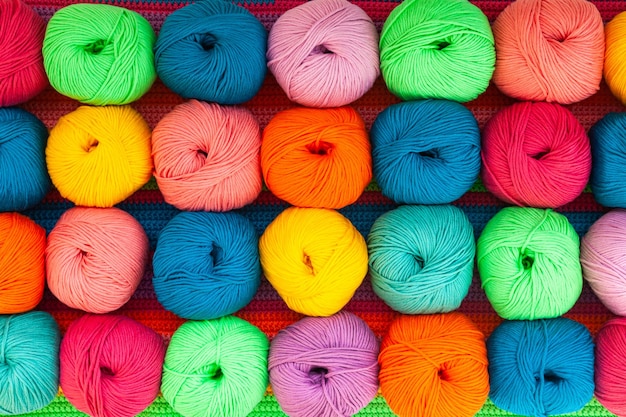 Many multicolored balls of threads on a knitted fabric closeup