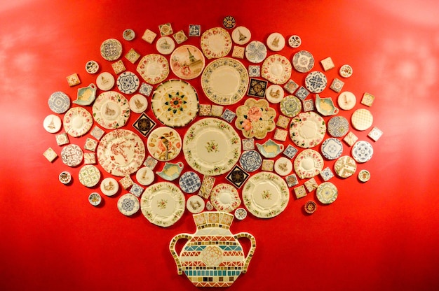 Many multicolored ceramic plates on a red wall background