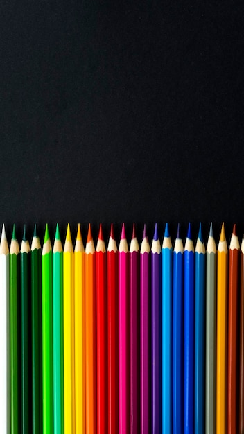 Many multicolored pencils on a black background