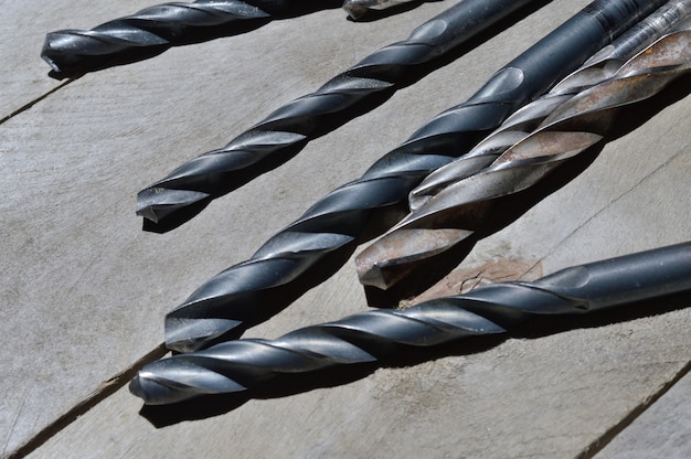 many old drills lie on a plank wooden background. close-up.