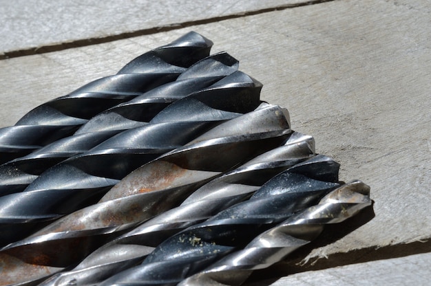 many old drills lie on a plank wooden background. close-up.