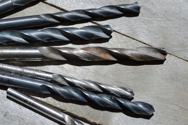 many old drills lie on a plank wooden background. close-up.