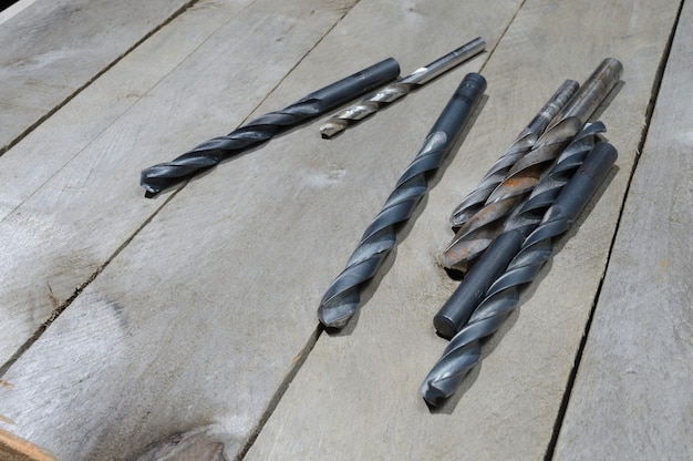 many old drills lie on a plank wooden background. close-up.
