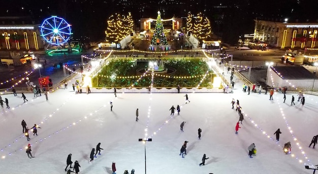 写真 オープンエアの美しいアイススケートリンクでスケートをする多くの人々が、新年のクリスマスイルミナを飾りました