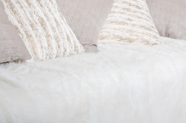 Many pillows lie on the couch, which is covered with a large plush veil