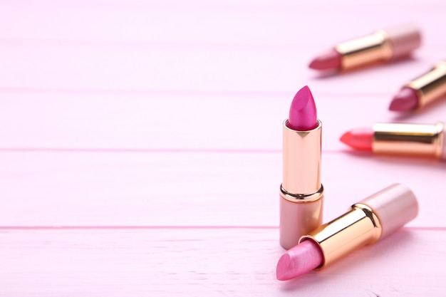 Many pink lipsticks on pink, close up