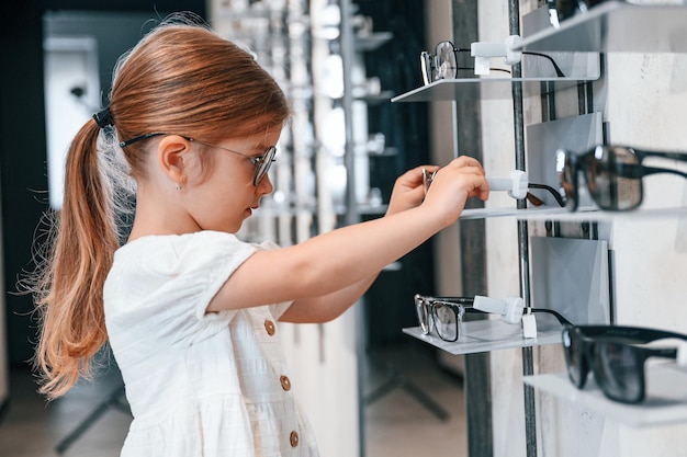 Many of the products Little girl in the glasses store choosing eyewear