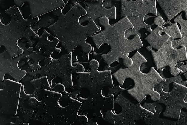 Many puzzles are randomly scattered on the plane Photo of black puzzles on a black background