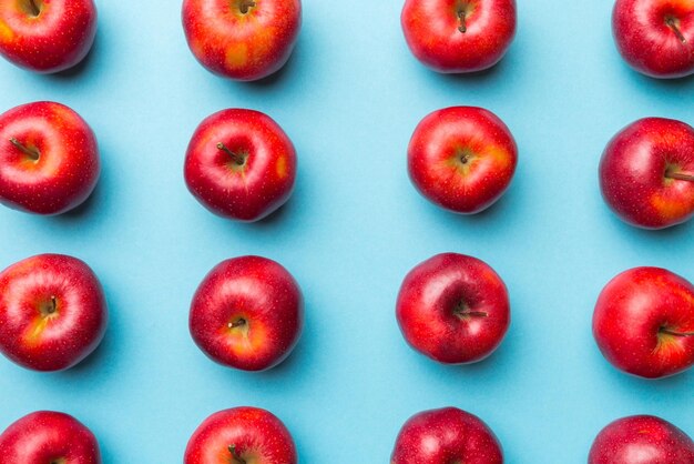 色付きの背景の上に多くの赤いリンゴがビューの上に新鮮なリンゴを持つ秋のパターンを表示します