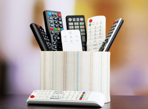 Many remote control devices in basket on bright background