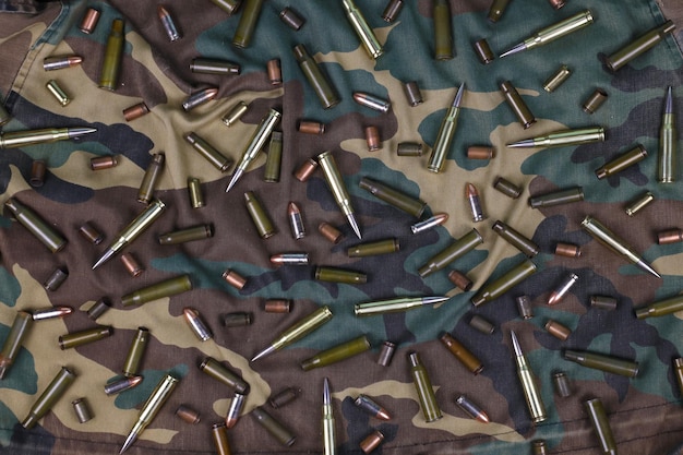 Many rifle bullets and cartridges on dark camouflage background