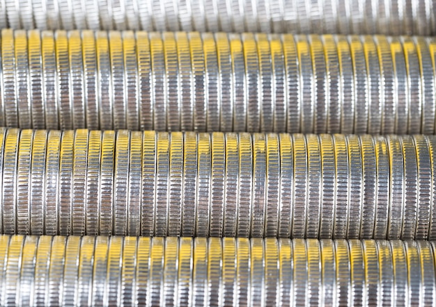 Many round metal coins of silver color illuminated in yellow, legal tender that is used for payments in the state, beautiful coins close-up with a yellow hue the same coin value