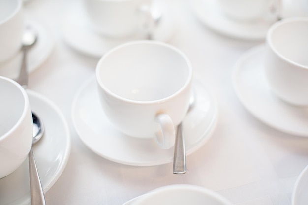 Many rows of white ceramic coffee or tea cups Lines of coffee cups in front of conference room