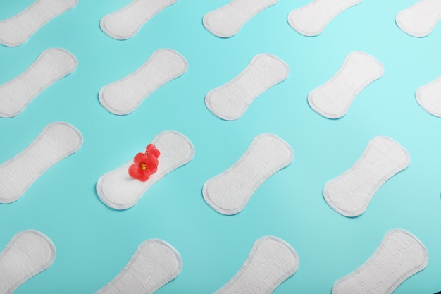 many sanitary pads on a blue background in the form of a diagonal pattern with a flower. textured background all over the screen.