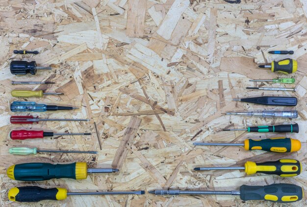 Many screwdrivers from small to large arranged in size on the OSB plate Place for text or logo