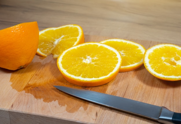 Фото Многие дольки апельсина лежат на деревянной кухонной доске. свежие цитрусовые.