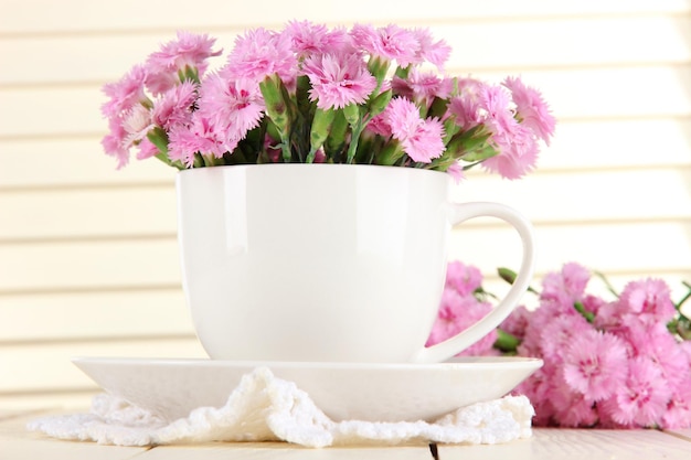 Photo many small pink cloves in cup on wooden background