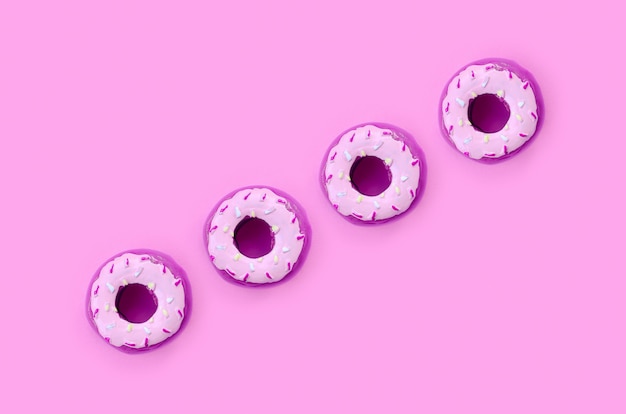 Many small plastic donuts lies on a pastel colorful background