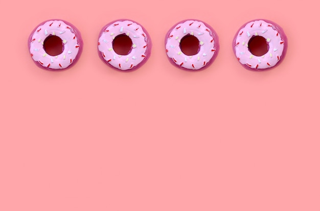 Many small plastic donuts lies on a pastel colorful. Flat lay minimal. Top view