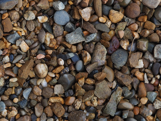 Many small wet stones close-up, horizontal pebble texture image with soft focus, blurred background and place for text