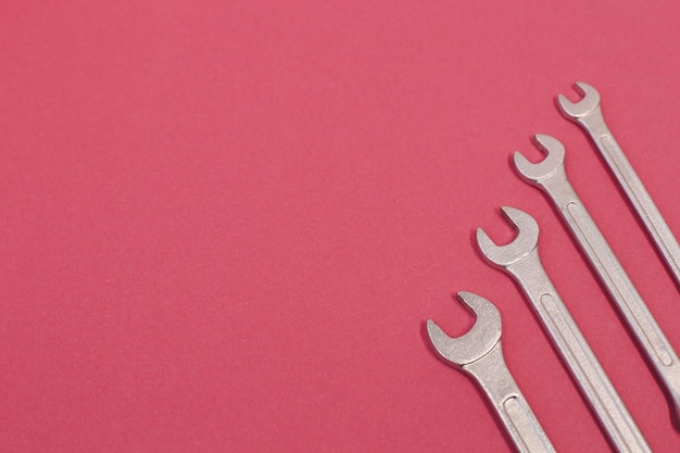 Many steel wrenches on an pink background full screen