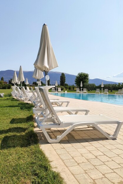 Many sun loungers by the water on a warm summer day relaxing by the pool on the beach