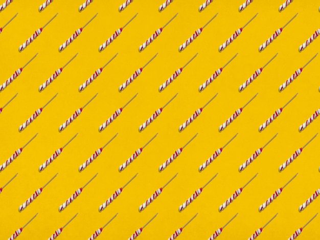 Many sweet lollipops arranged in rows on yellow background