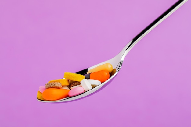 Many tablets on a spoon isolated on a red background