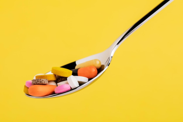 Many tablets on a spoon isolated on a yellow background.