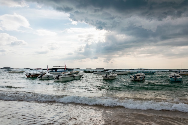 Molte barche e yacht tradizionali sul mare o sull'oceano. un'imminente tempesta tropicale con pioggia e nuvole di pioggia scure nel cielo e il sole che le attraversa