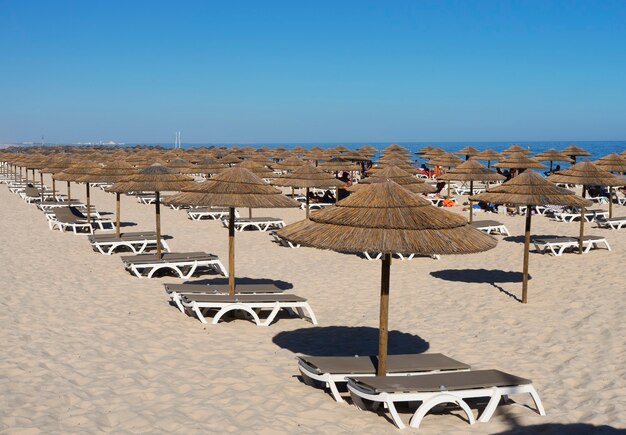 Molti ombrelloni sulla spiaggia con cielo blu nell'isola di tavira, portogallo