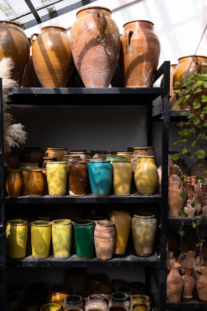 Many unique handmade colorful clay jugs and vases of various shapes on shelf in local market