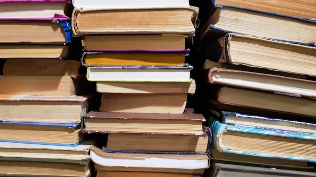 Many used old books in the school library. chaotic layout of stacks of literature, selective focus. A pile of books ends with stacked background. books in a library - backdrop.