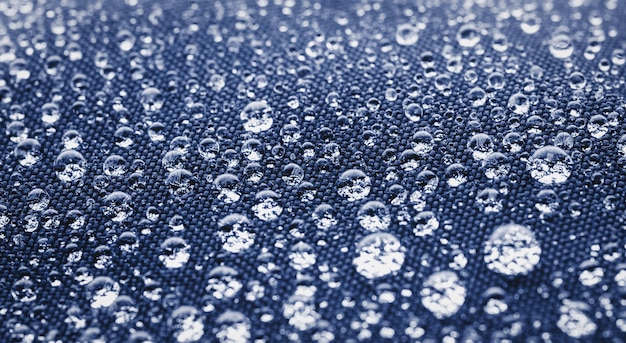 Many water drops on dark blue waterproof fabric