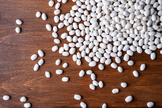 Many white beans poured on a wooden background Concept healthy eating and vegetarianism